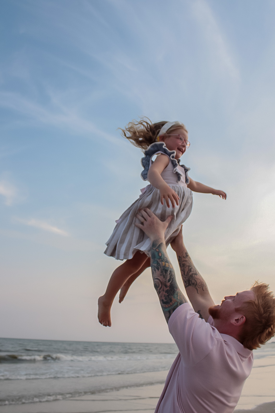 Father lifting his daughter playfully during a beach photography session
